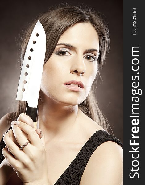 Mysterious brunette poses with a dangerous knife in a seductive fashion. Mysterious brunette poses with a dangerous knife in a seductive fashion.