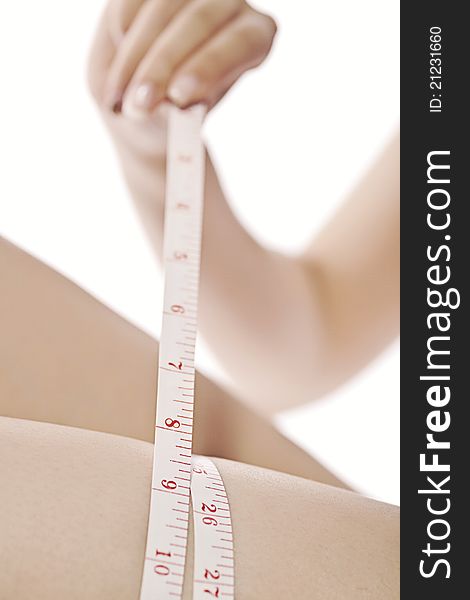 Close up of a woman measuring her leg with a white centimeter on a white background. Close up of a woman measuring her leg with a white centimeter on a white background.
