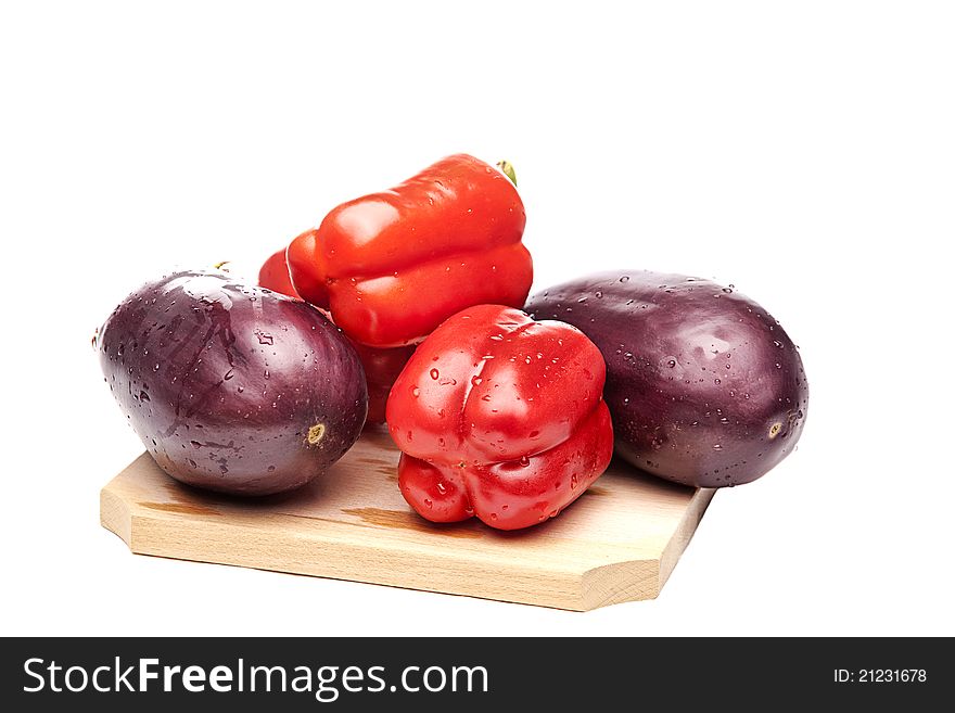Red peppers and eggplants on a wood cutting board with a white centimeter on a white background. Red peppers and eggplants on a wood cutting board with a white centimeter on a white background.