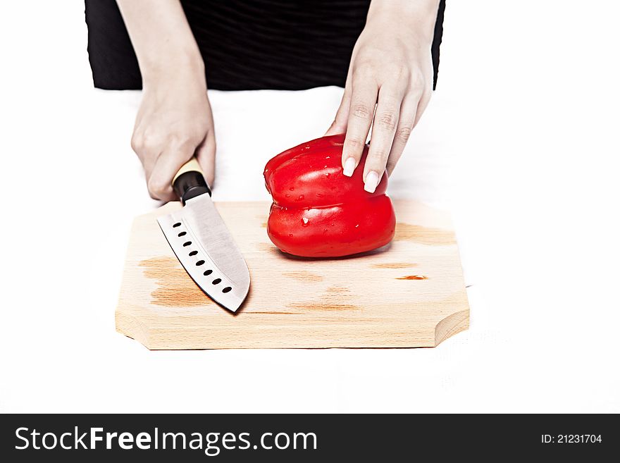 Woman in a black dress is preparing to cut a red pepper on a wood cutting board. Woman in a black dress is preparing to cut a red pepper on a wood cutting board.