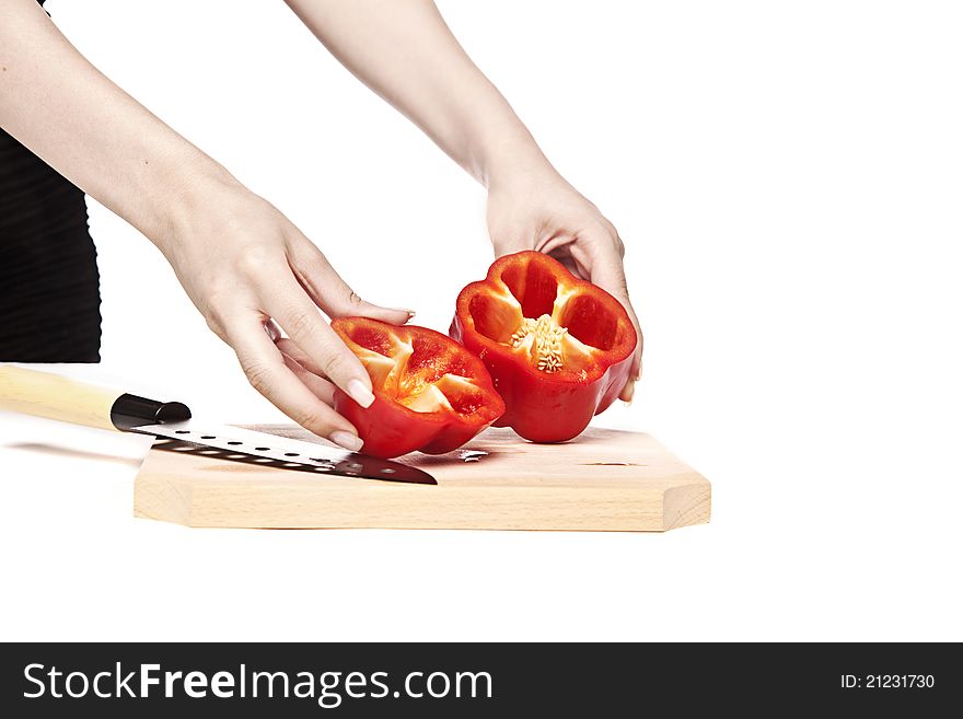 Woman splits a red pepper in half on a wood cutting board. Woman splits a red pepper in half on a wood cutting board.