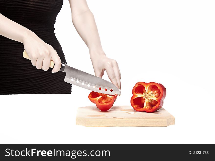 Woman cutting a perfect red pepper on a wood cutting board with a sharp kitchen knife. Woman cutting a perfect red pepper on a wood cutting board with a sharp kitchen knife.