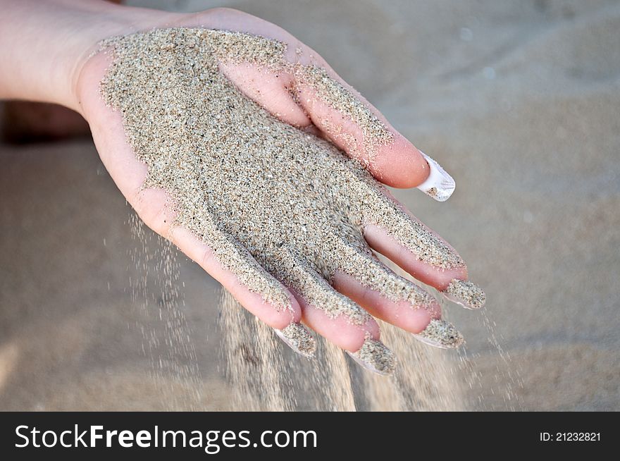Sand pours from the hands on the beach. Sand pours from the hands on the beach