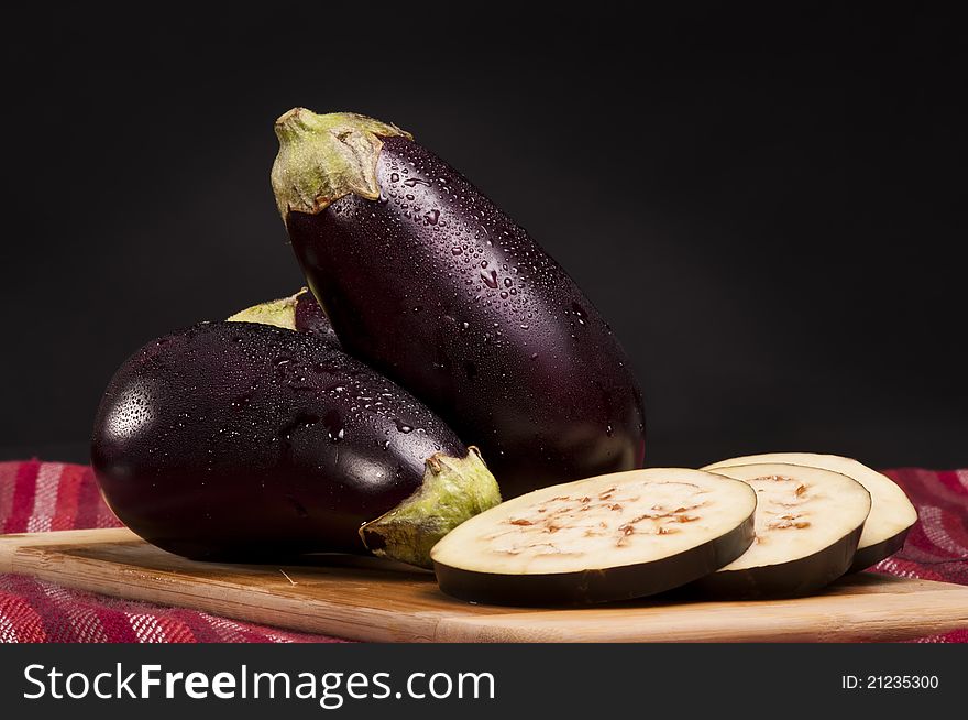 Whole and slices of eggplants on a cutting board