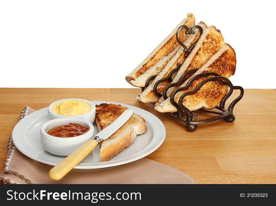 Toast, marmalade and butter on a plate with toast in a rack on a wooden table. Toast, marmalade and butter on a plate with toast in a rack on a wooden table