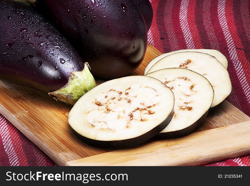 Whole and slices of eggplants on a cutting board