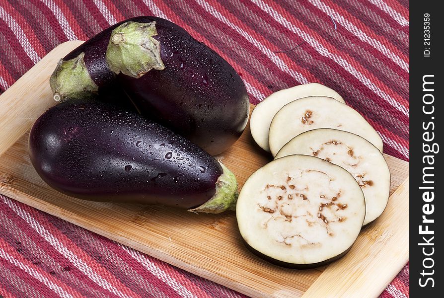 Whole and slices of eggplants on a cutting board