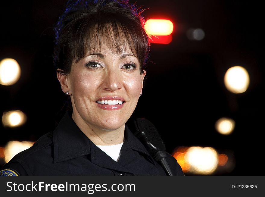 A Hispanic female police officer standing in the night with her police car in the background. A Hispanic female police officer standing in the night with her police car in the background.