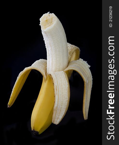 Peeled banana with a bite out of it on a dark background