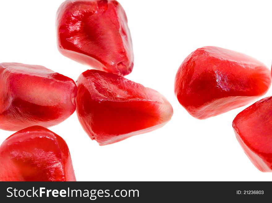 Macro a photo of mature red grains of a pomegranate on a white background. Macro a photo of mature red grains of a pomegranate on a white background