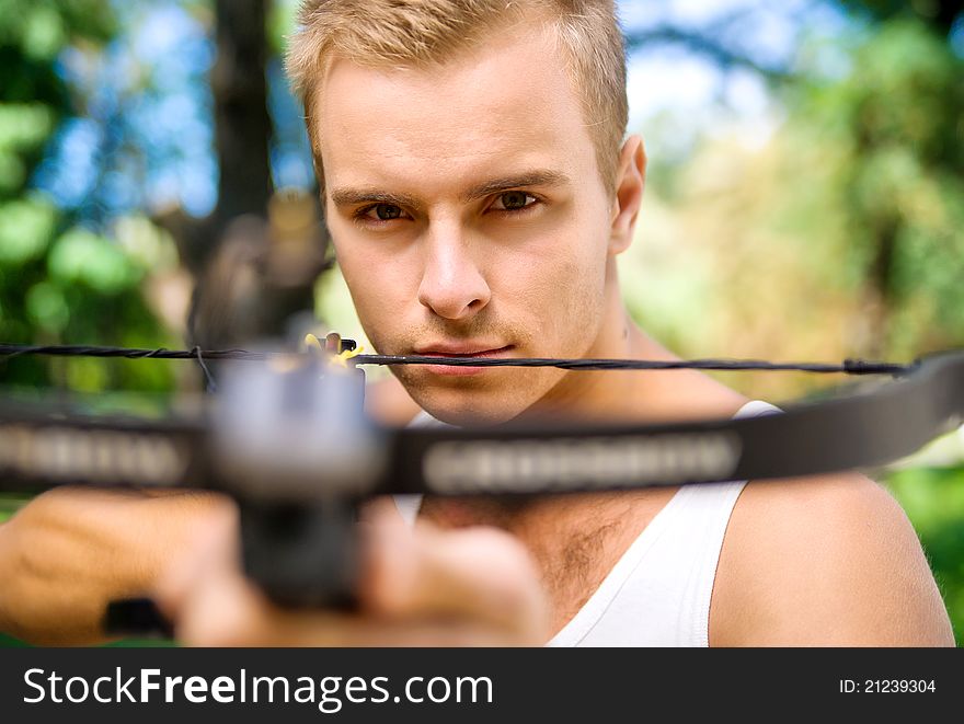 Strong young man with arbalest on the wood background. Strong young man with arbalest on the wood background