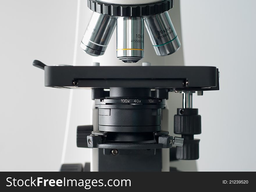 Front of proffesional microscope on clear gray background