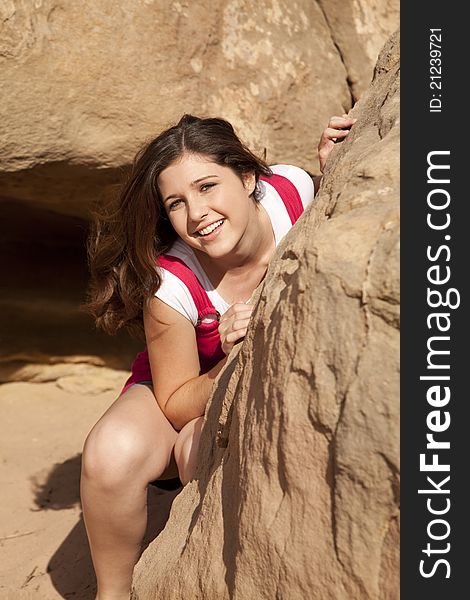 A girl with a big smile on her face hiding behind a rock in the outdoors. A girl with a big smile on her face hiding behind a rock in the outdoors.