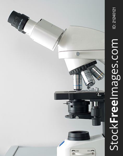 Right side of professional medical microscope on gray background