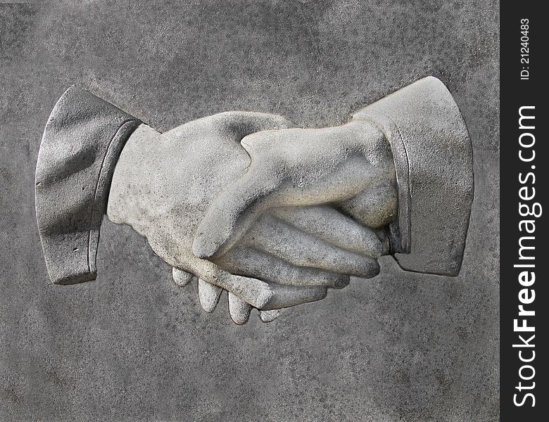 Stone carving of two hands in a handshake. Stone carving of two hands in a handshake.
