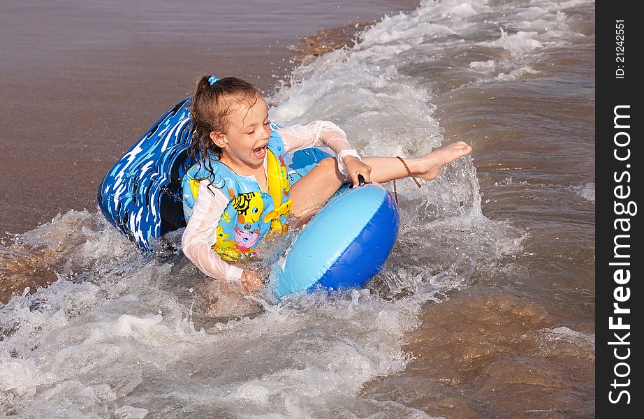 Child rides a wave of the sea.
