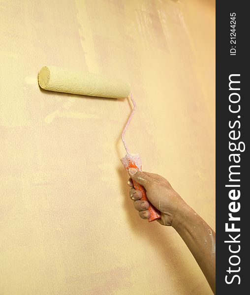 Painting a wall with a paint rol with yellow paint. Painting a wall with a paint rol with yellow paint
