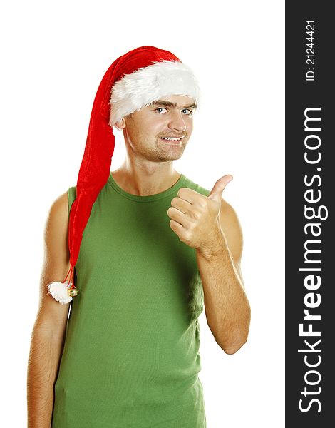 Young man in a Santa Claus hat and green poppy approvingly shows the thumb raised up. Isolated on a white background. Young man in a Santa Claus hat and green poppy approvingly shows the thumb raised up. Isolated on a white background