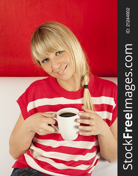 Young Woman Sitting On A Sofa Drinking Coffee