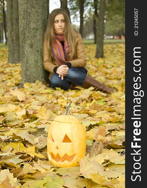 Young girl outdoors in autumn in the park with a pumpkin for Halloween