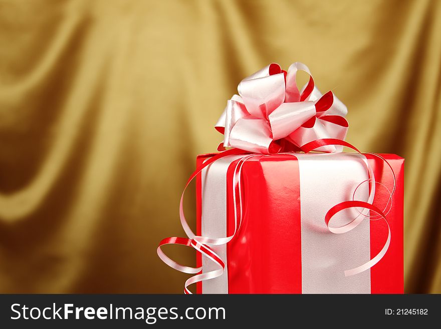 Christmas gift in a red box with a silver bow on golden background