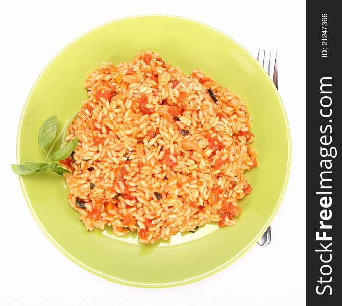 Risotto with tomatoes on a green plate decorated with basil