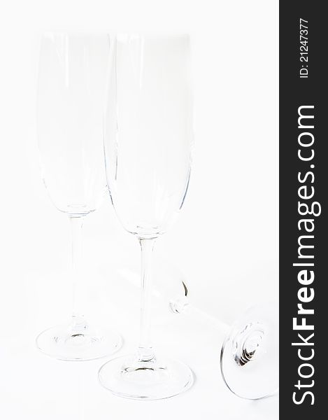 Group of empty champagne glasses on a white background, the two stand side by side, one lying on its side