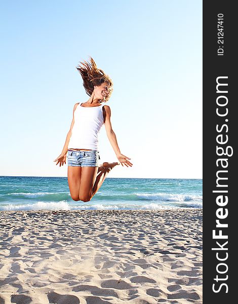 Young woman jumping on sand beach. Young woman jumping on sand beach