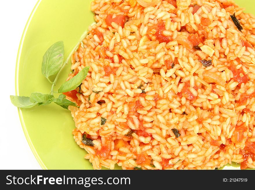 Risotto with tomatoes on a green plate decorated with basil