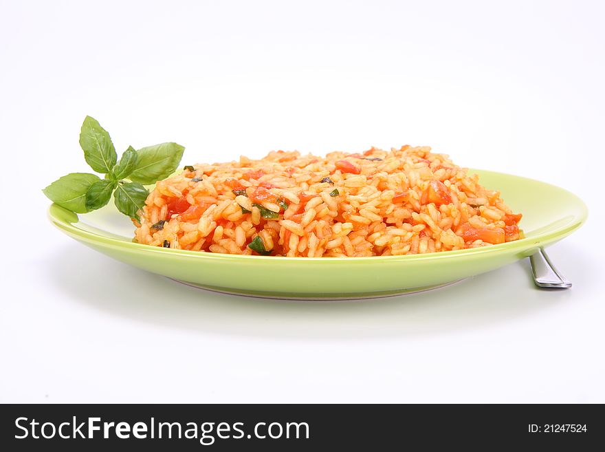 Risotto with tomatoes on a green plate decorated with basil