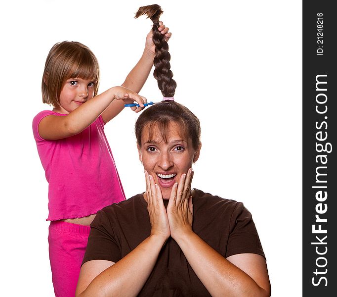 Little girl with a devilish grin about to cut moms pony tail off. Little girl with a devilish grin about to cut moms pony tail off.