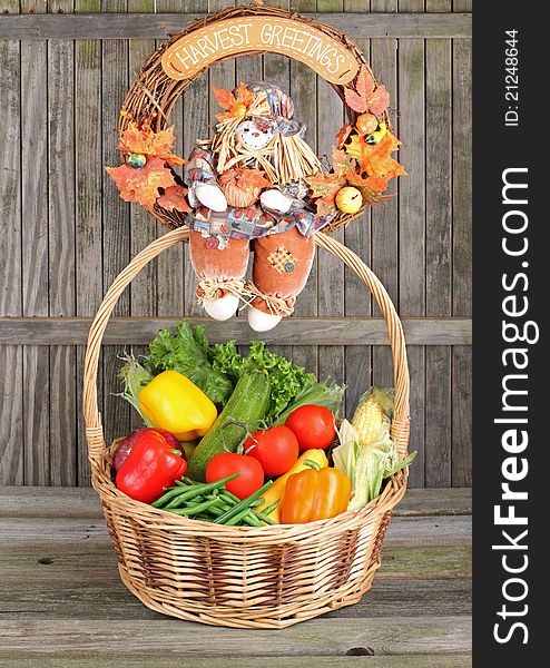 Harvest wreath sitting on top of a basket of vegetables against a weathered fence. Harvest wreath sitting on top of a basket of vegetables against a weathered fence