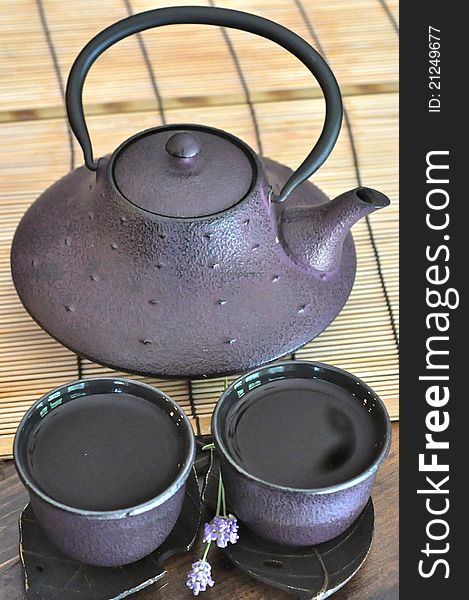 Traditional Chinese tea kettle with 2 cups on saucers for drinking tea with bamboo backround. Traditional Chinese tea kettle with 2 cups on saucers for drinking tea with bamboo backround