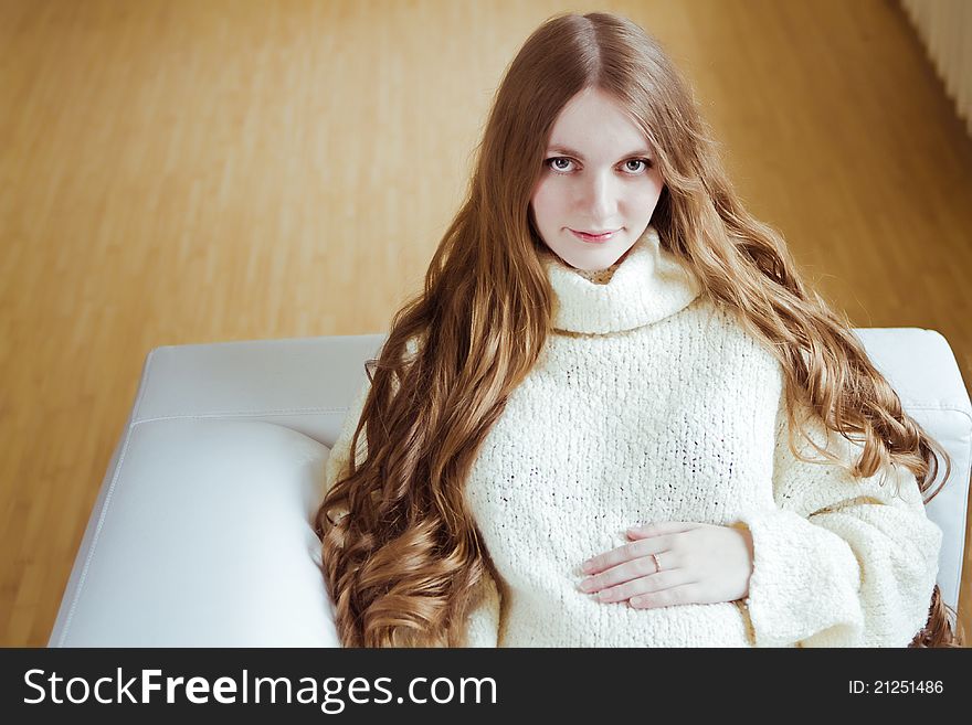 Beautiful young pregnant woman sitting on sofa