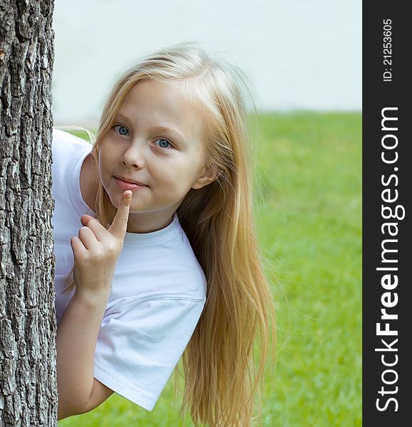 Girl hiding behind a tree in a white shirt. Girl hiding behind a tree in a white shirt