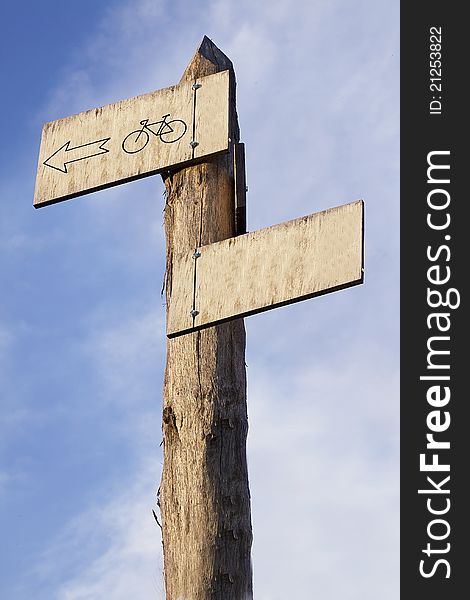 A wooden signpost on a sky background showing a bike route