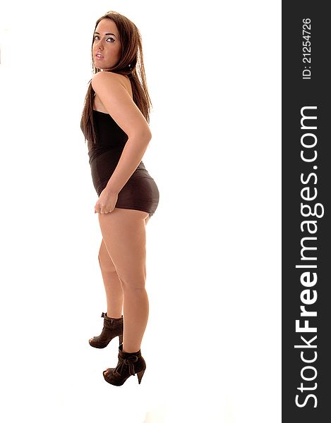 Pretty woman with nice figure standing in heels and a short black dress in profile in the studio, for white background. Pretty woman with nice figure standing in heels and a short black dress in profile in the studio, for white background.