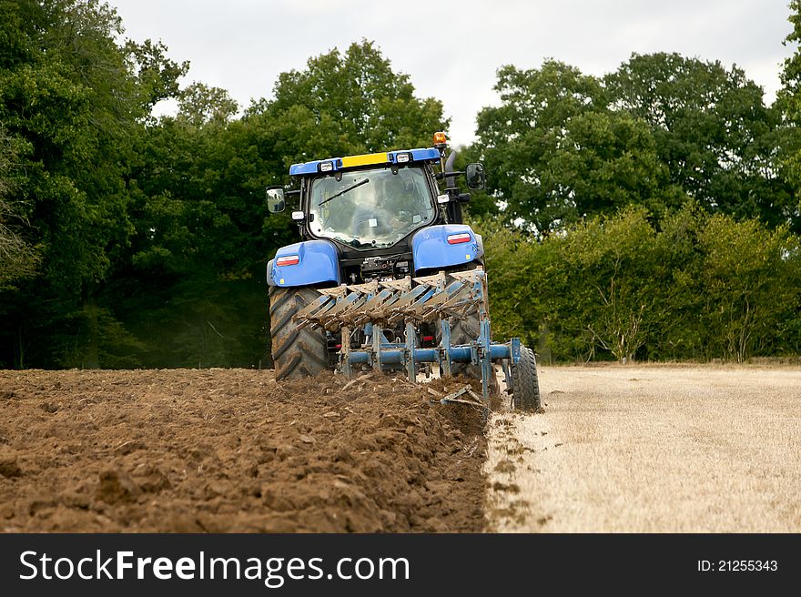 Tractor speeding away from camera towing a plough. Tractor speeding away from camera towing a plough.