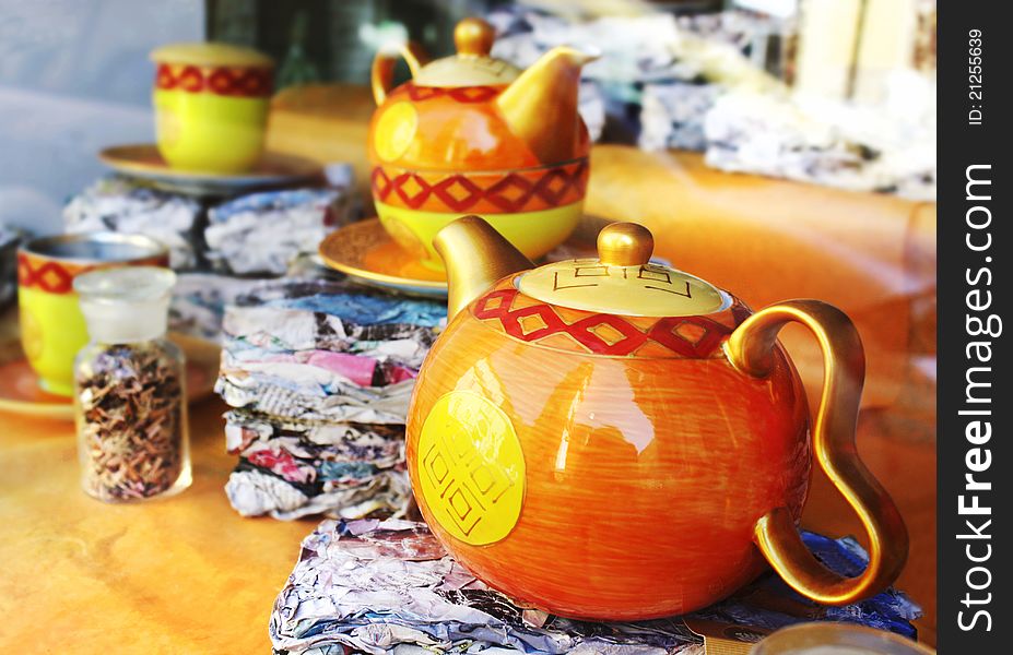 Decorated teapots and teacups in the background in the window