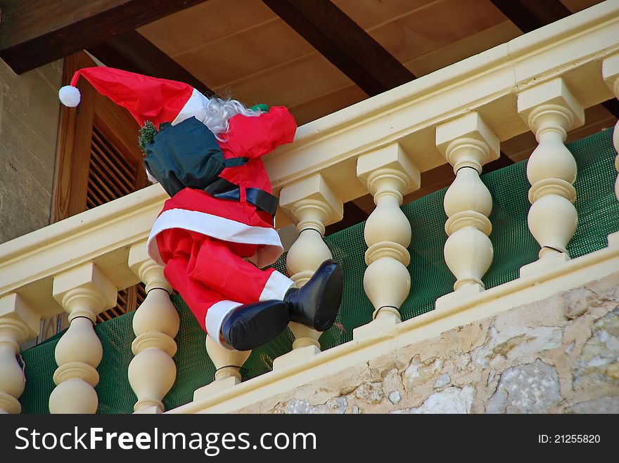 Santa Claus Puppet climbing on the balcony of a house to deliver the presents. Santa Claus Puppet climbing on the balcony of a house to deliver the presents
