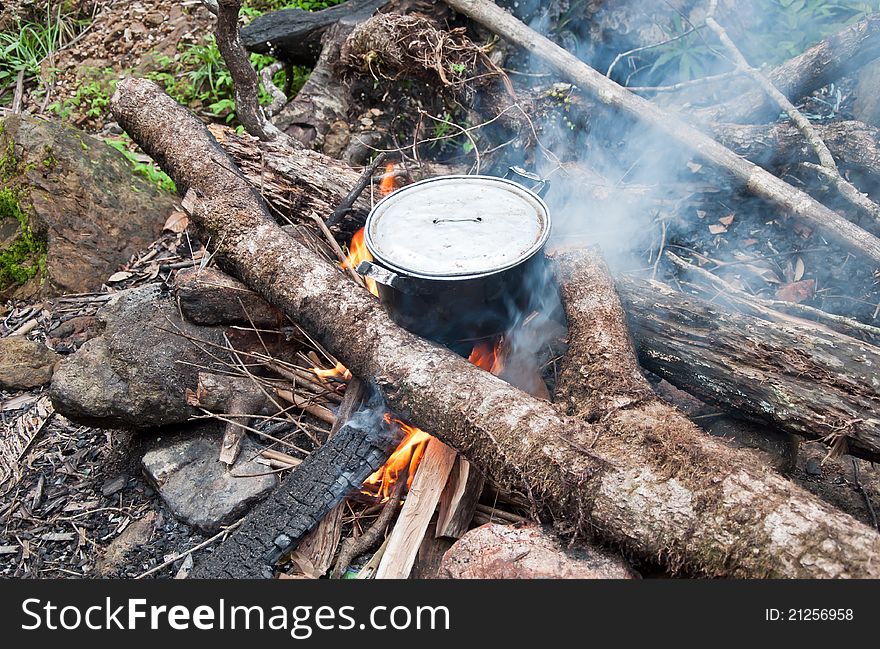 A can over an open fire with dinner for tourists after a long day of walk in the mountains. A can over an open fire with dinner for tourists after a long day of walk in the mountains.