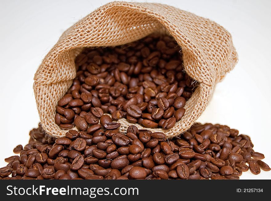 Grains of the coffee spilling out from the sack on the white background. Grains of the coffee spilling out from the sack on the white background