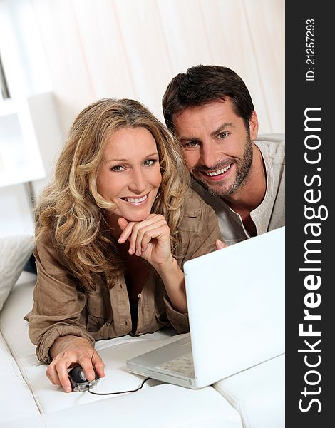 Couple smiling on laptop in their home. Couple smiling on laptop in their home.