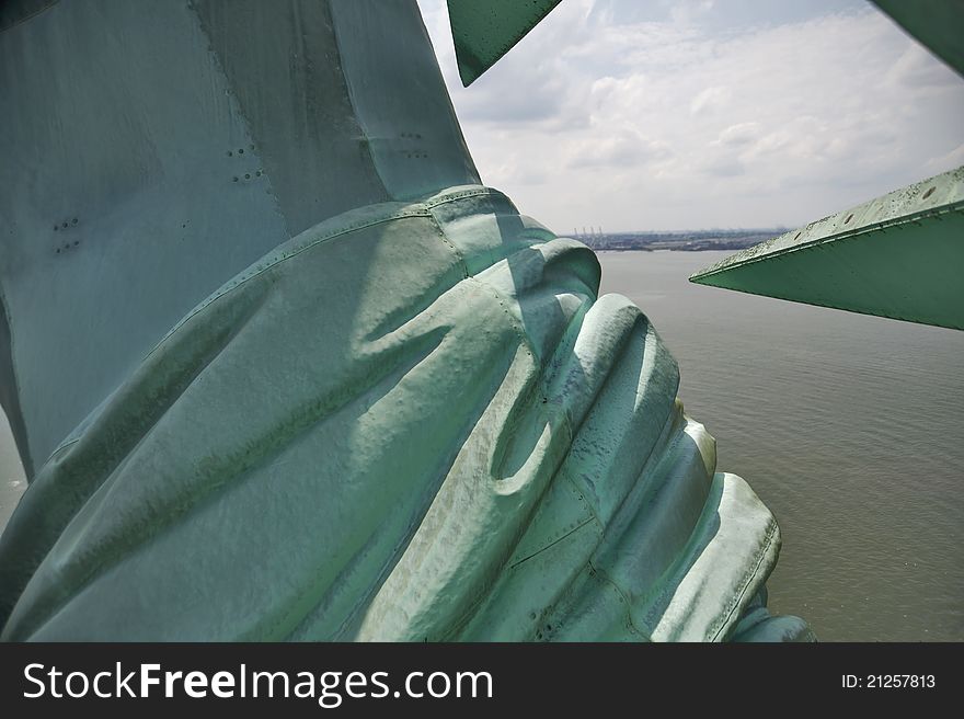 View past the Statue of Liberty's shoulder as seen from her crown with New York Harbor in the distance. View past the Statue of Liberty's shoulder as seen from her crown with New York Harbor in the distance.