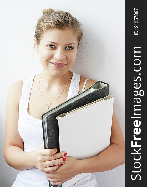 Teenage girl with books in her arms smiling at the camera