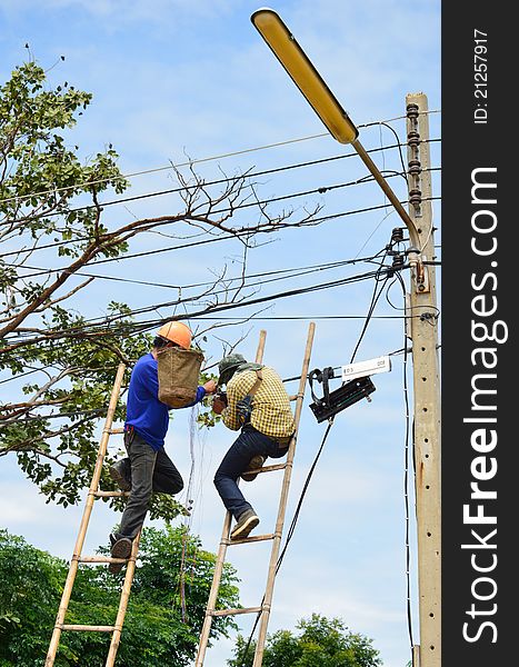 A lineman working on cable - telephone pole from ladder