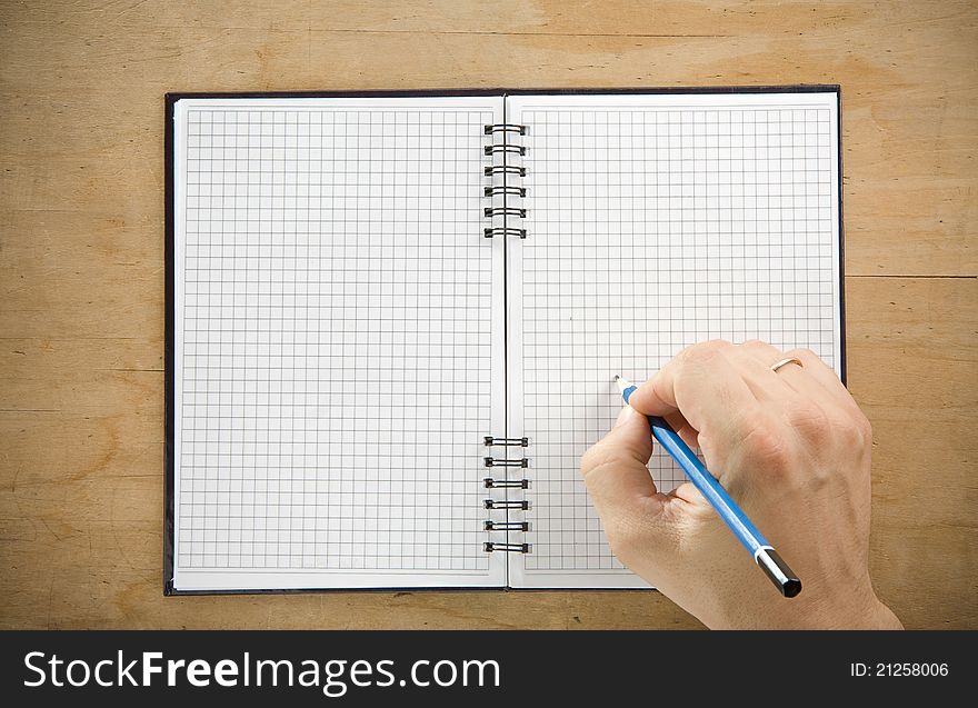 Male hand writing by pencil on checked notebook