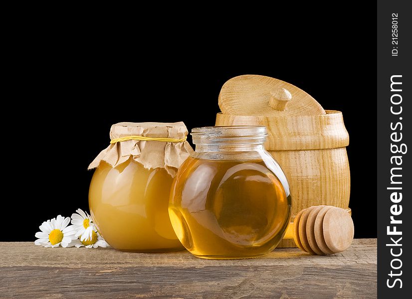 Jar full of honey and stick on blackbackground