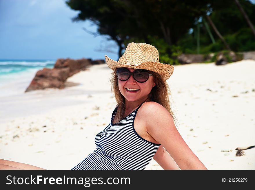 Happy woman in cowboy hat resting on a beach