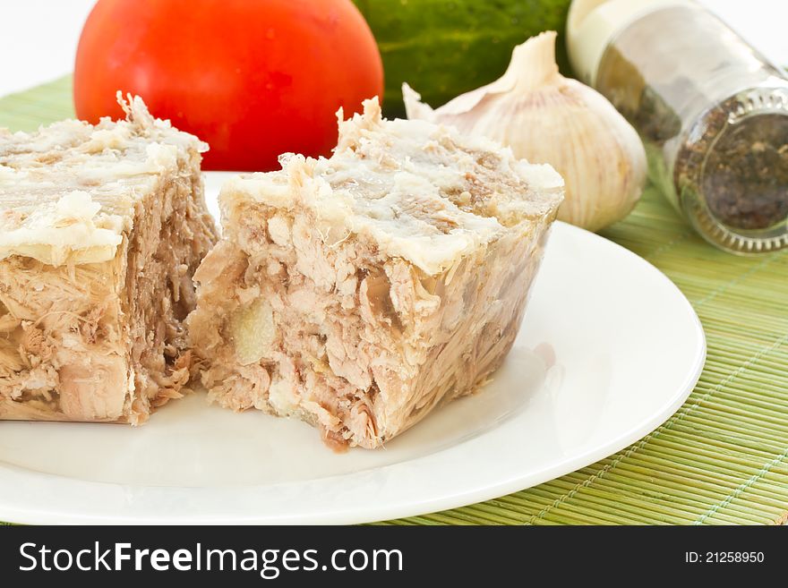 Jellied meat on a white plate against the vegetables